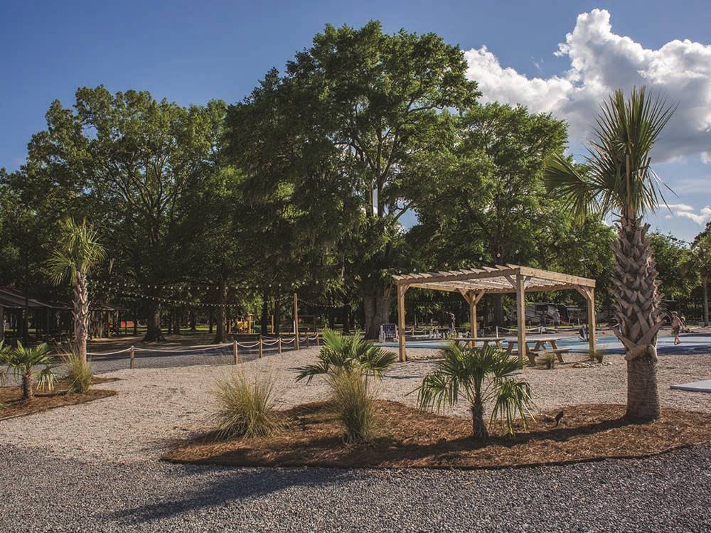 Picnic benches under a gazebo next to the pool at PALMETTO SHORES RV RESORT