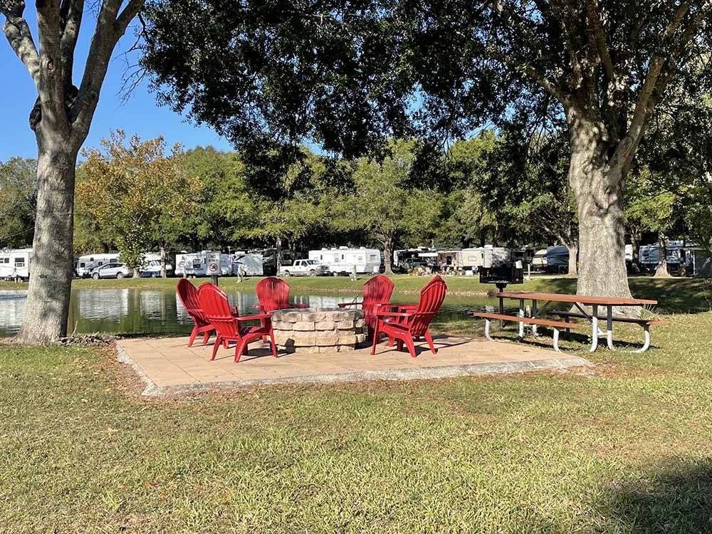 Red Adirondack chairs arrayed around a fire pit at GAINESVILLE RV PARK
