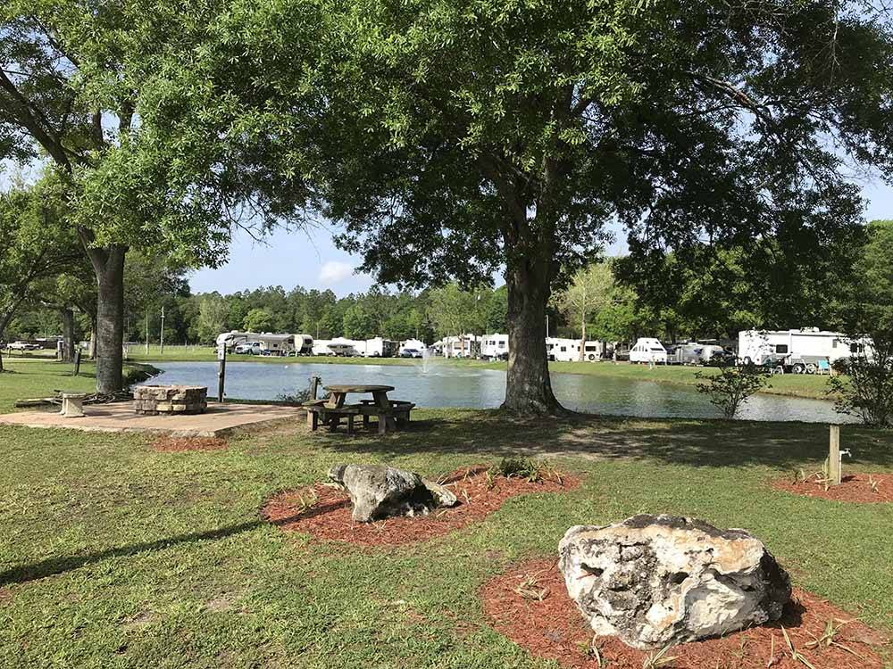 Picnic area with pond and RVs on opposite bank at GAINESVILLE RV PARK