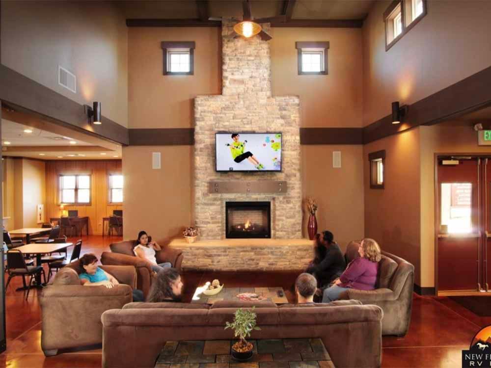 People watching the TV above the fireplace in the main room at NEW FRONTIER RV PARK