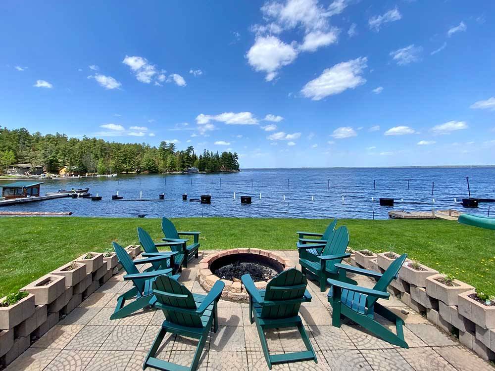 Chairs surrounding fire pit near water at PINES OF KABETOGAMA RESORT