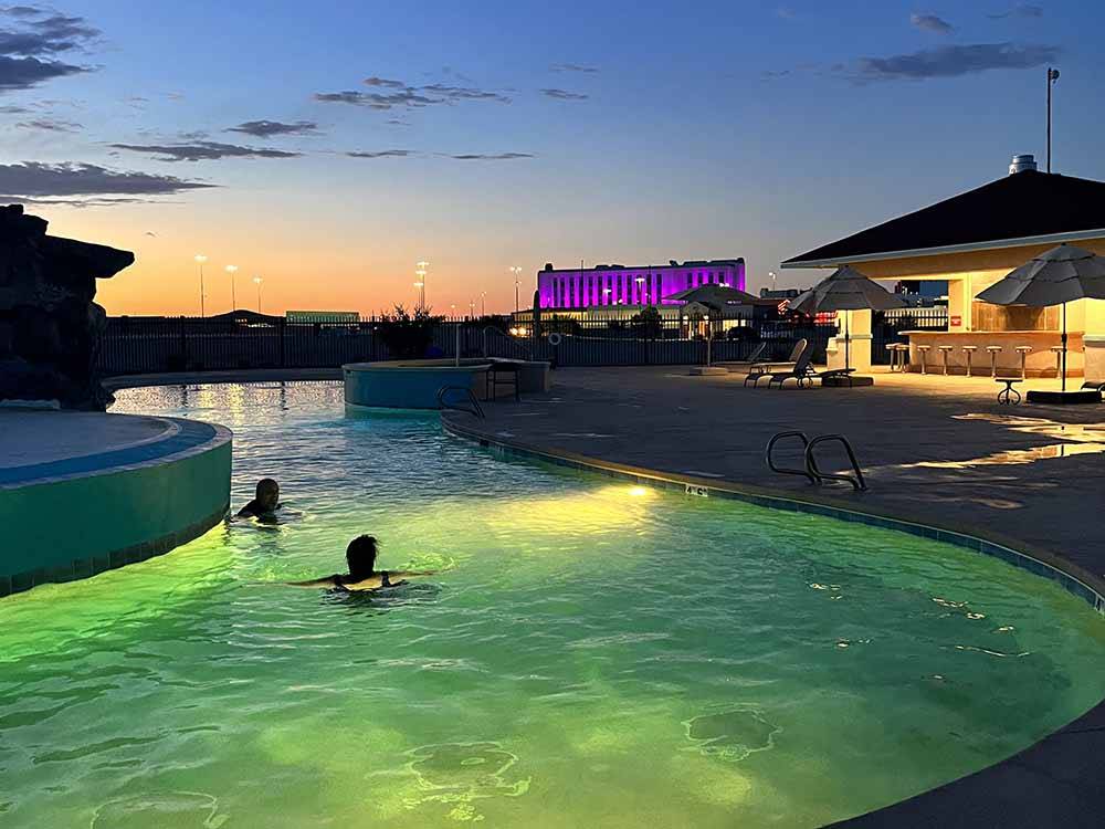 Two people in the swimming pool at night at ROUTE 66 RV RESORT