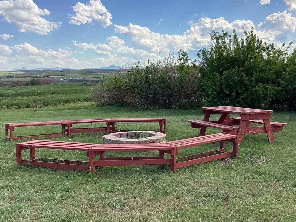 Fire ring surrounded by wooden benches at SLEEPING WOLF CAMPGROUND & RV PARK