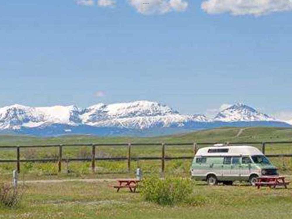 Camping van with towering snow-capped mountains on horizon at SLEEPING WOLF CAMPGROUND & RV PARK