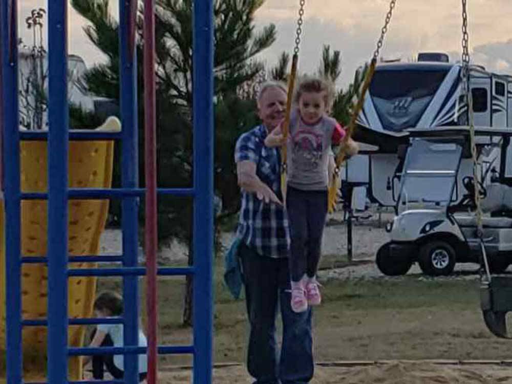 A man pushing a girl in a swing at RV CORRAL