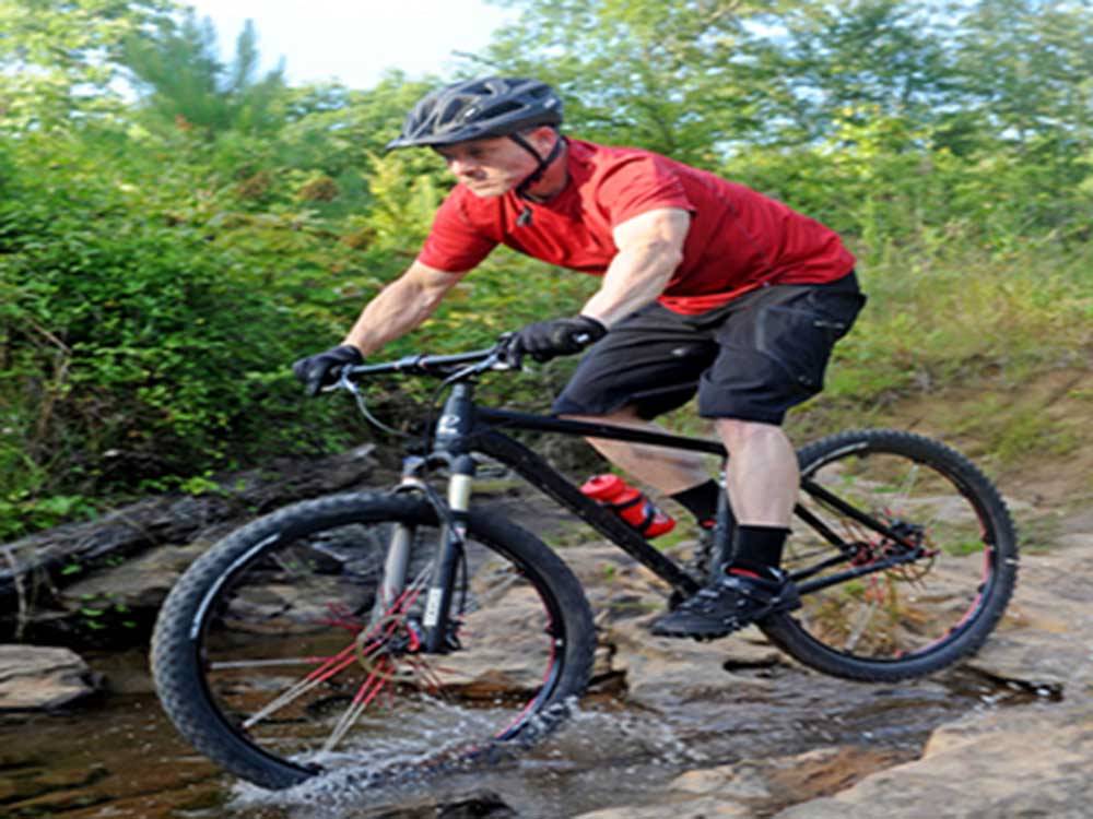 An man with a helmet mountain biking at THE COVE LAKESIDE RV RESORT AND CAMPGROUND