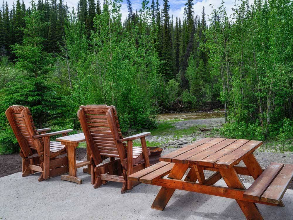Chairs and a bench on a patio looking at the river at RANCH HOUSE LODGE & RV CAMPING