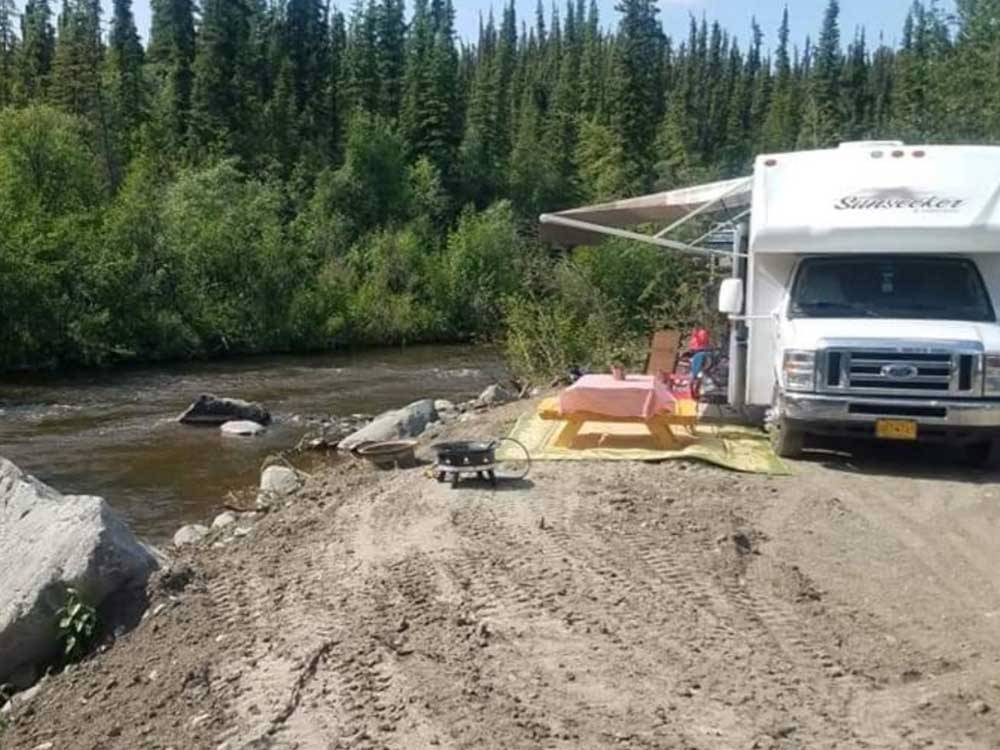 A camper parked next to the river at RANCH HOUSE LODGE & RV CAMPING
