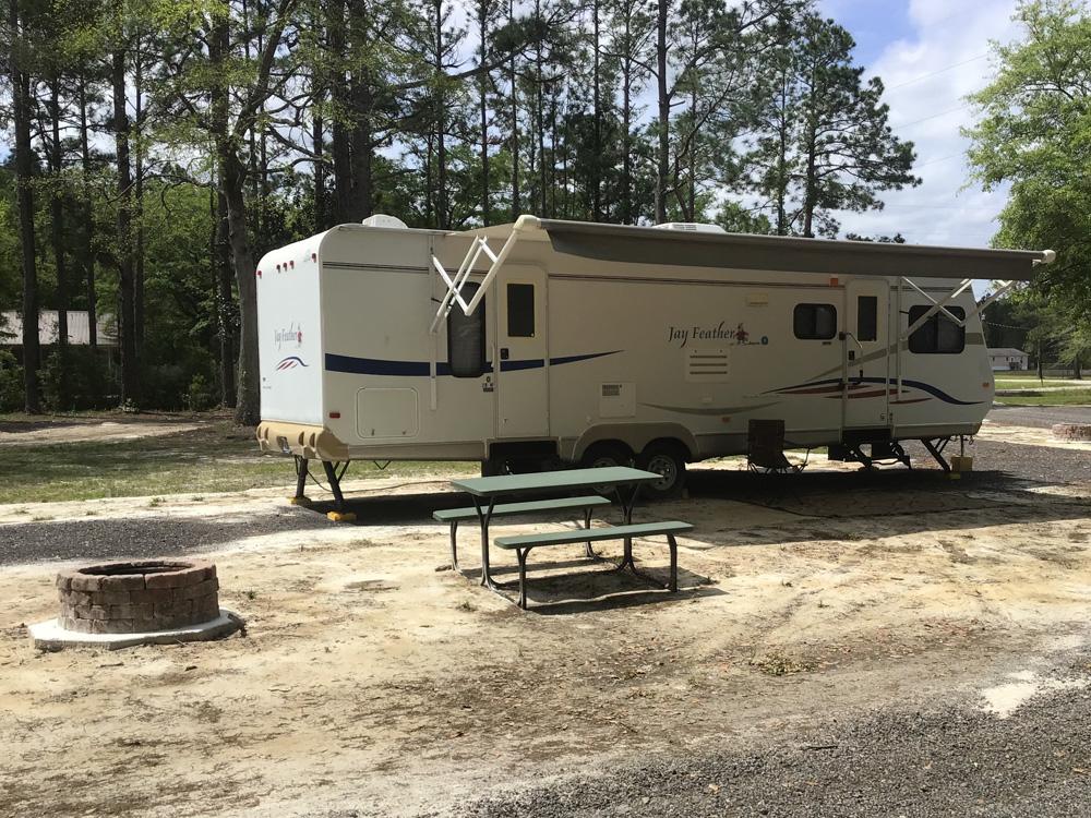 A travel trailer parked in a RV site at OKEFENOKEE PASTIMES CABINS & CAMPGROUND