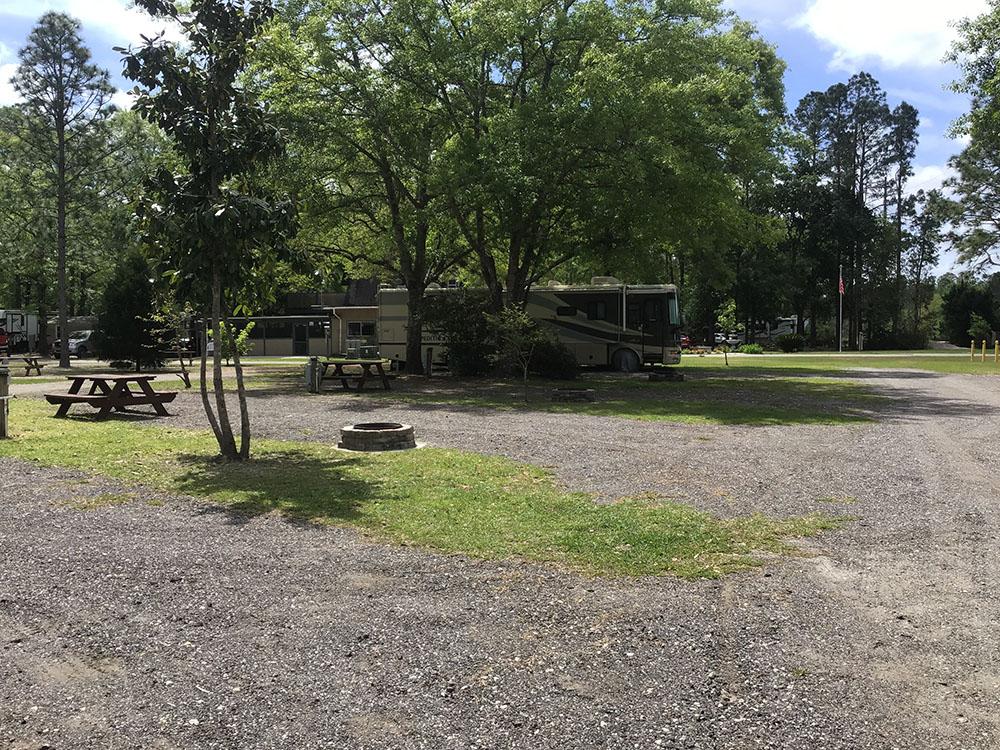 A gravel RV site with a fire pit and bench at OKEFENOKEE PASTIMES CABINS & CAMPGROUND