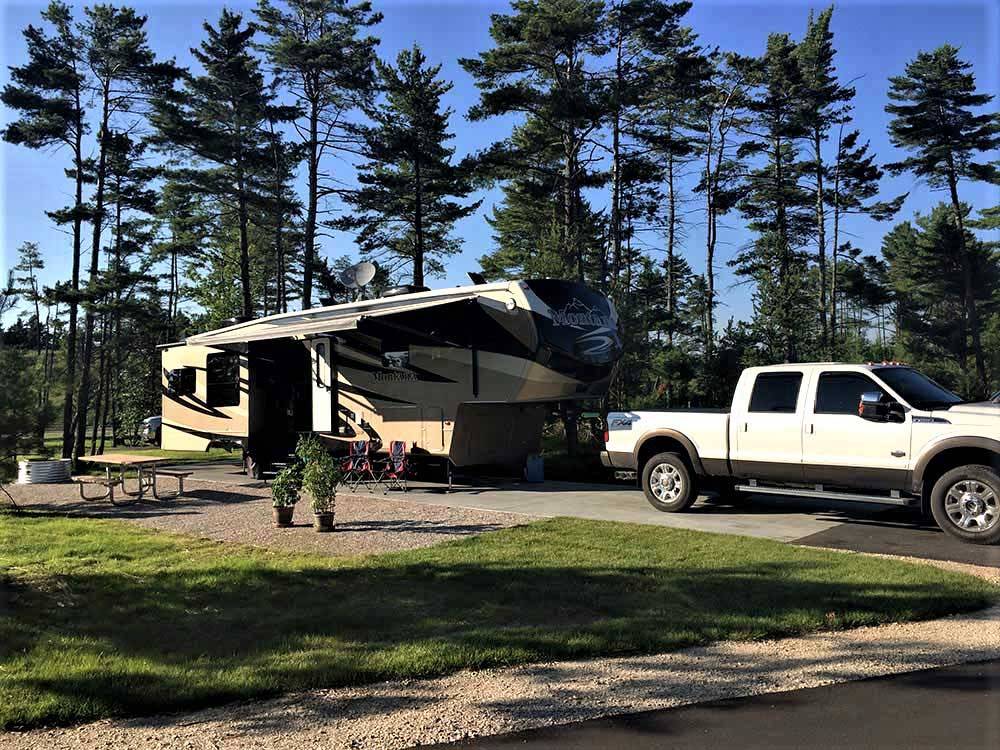 Fifth-wheel with truck on paved site at MANISTIQUE LAKESHORE CAMPGROUND