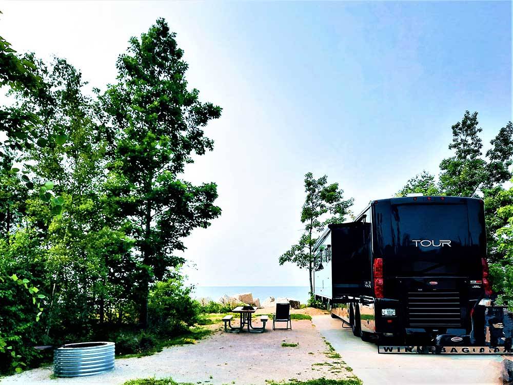 A Winnebago Tour parked next to the water at MANISTIQUE LAKESHORE CAMPGROUND