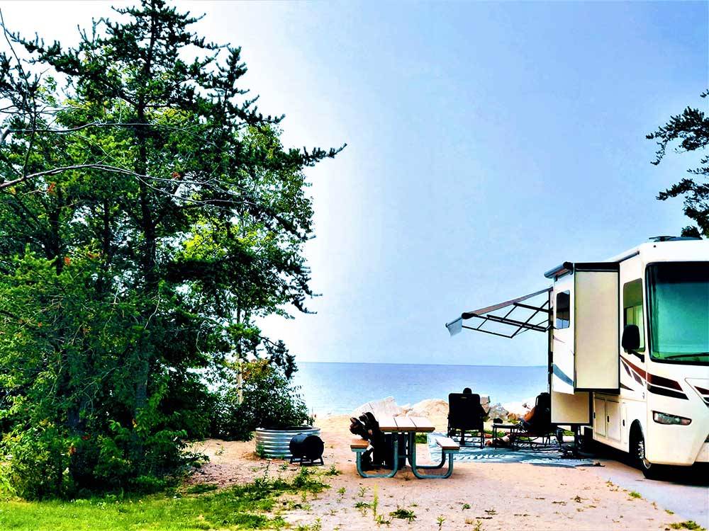 A motorhome parked by the water at MANISTIQUE LAKESHORE CAMPGROUND