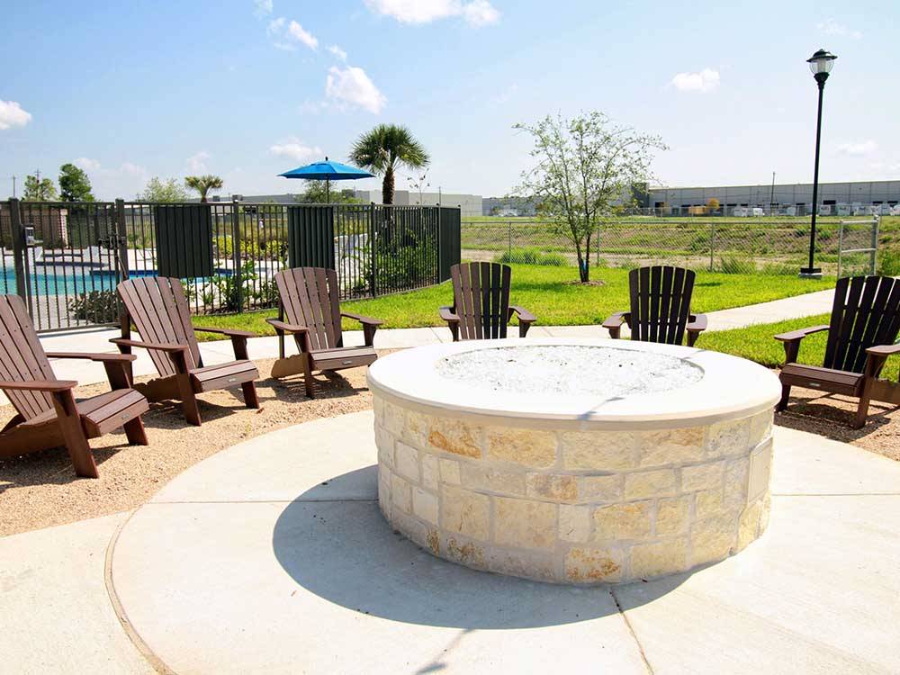 A large cement fire pit with lounge chairs at JETSTREAM RV RESORT - TROPICAL TRAILS