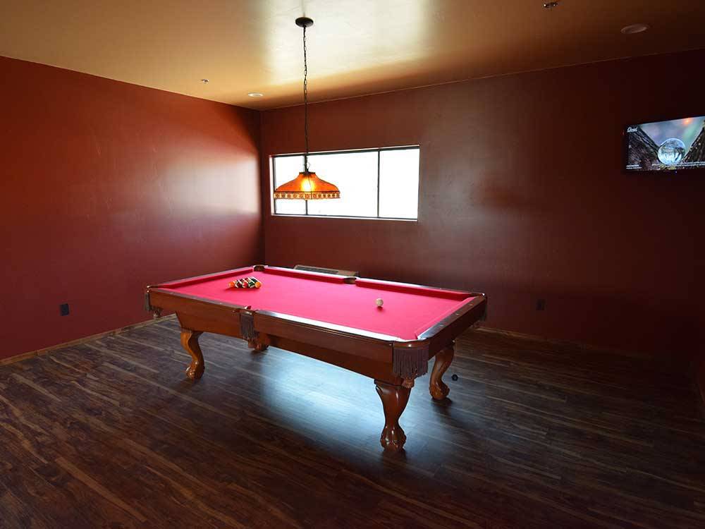 A pool table with red felt top at RAIN SPIRIT RV RESORT