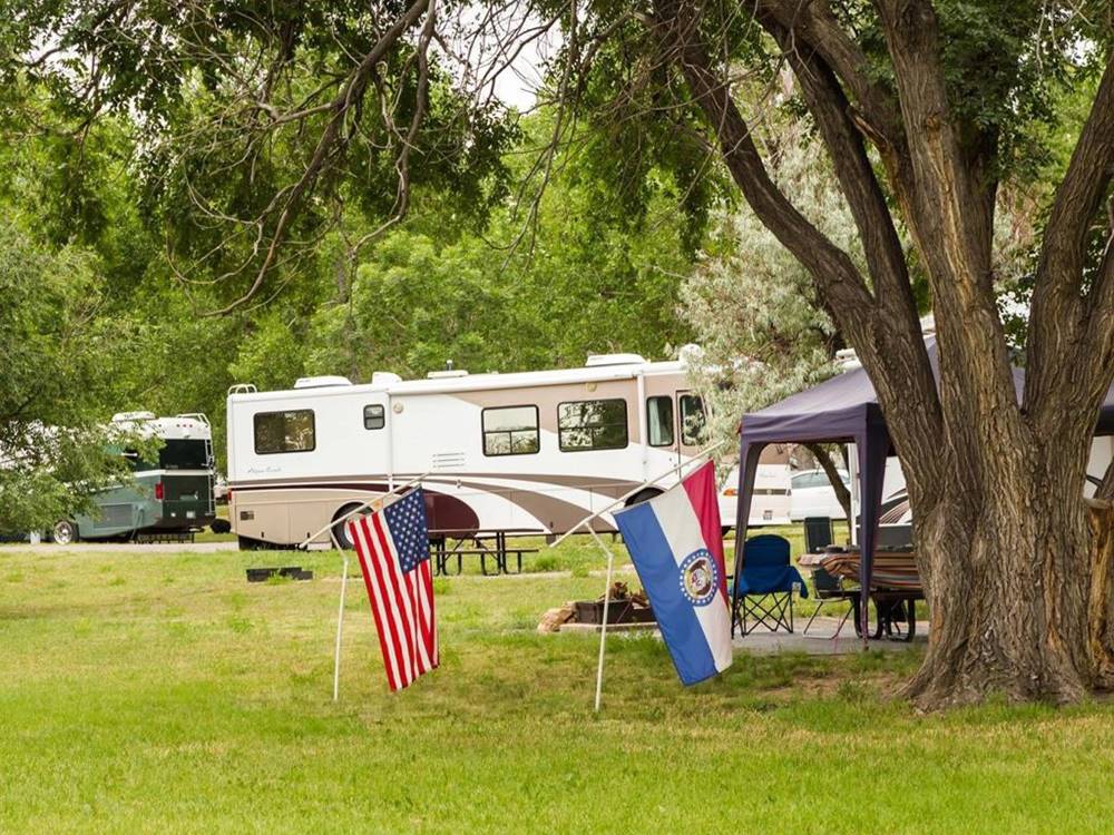 A parked Class-A RV and flags in the grass at The Oaks at Zephyrhills