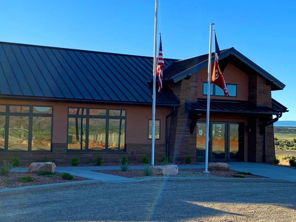 Main office building with flags hanging at GRAND PLATEAU RV RESORT AT KANAB