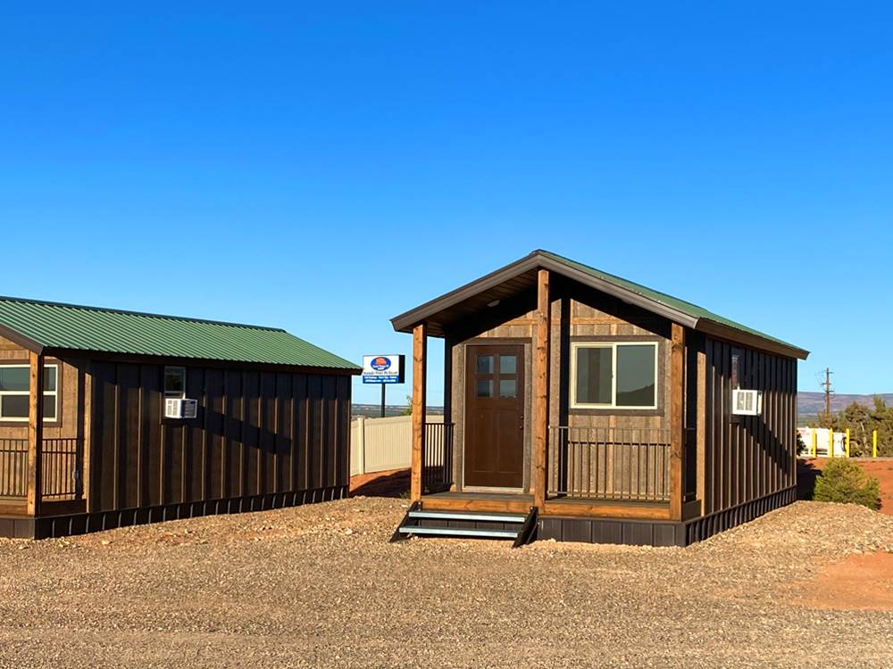 Two log cabins with a green roof at GRAND PLATEAU RV RESORT AT KANAB