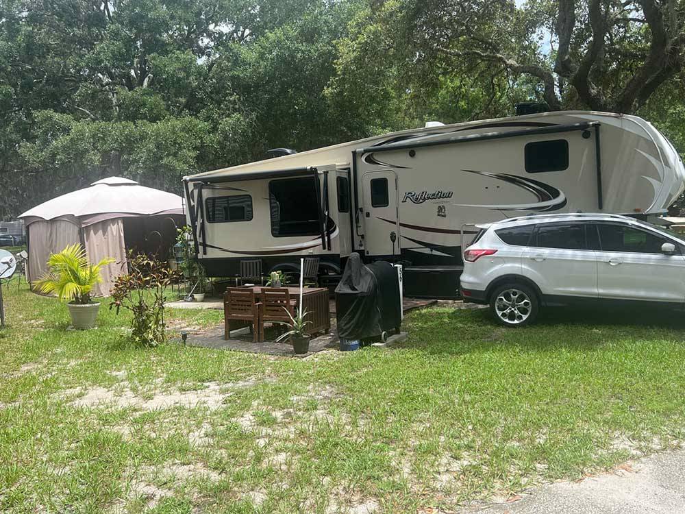 A fifth wheel trailer and car in a RV space at LOST LAKE RV PARK