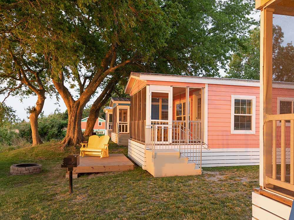 A colorful rental cabin with chairs in the front at OUTER BANKS WEST/CURRITUCK SOUND KOA HOLIDAY