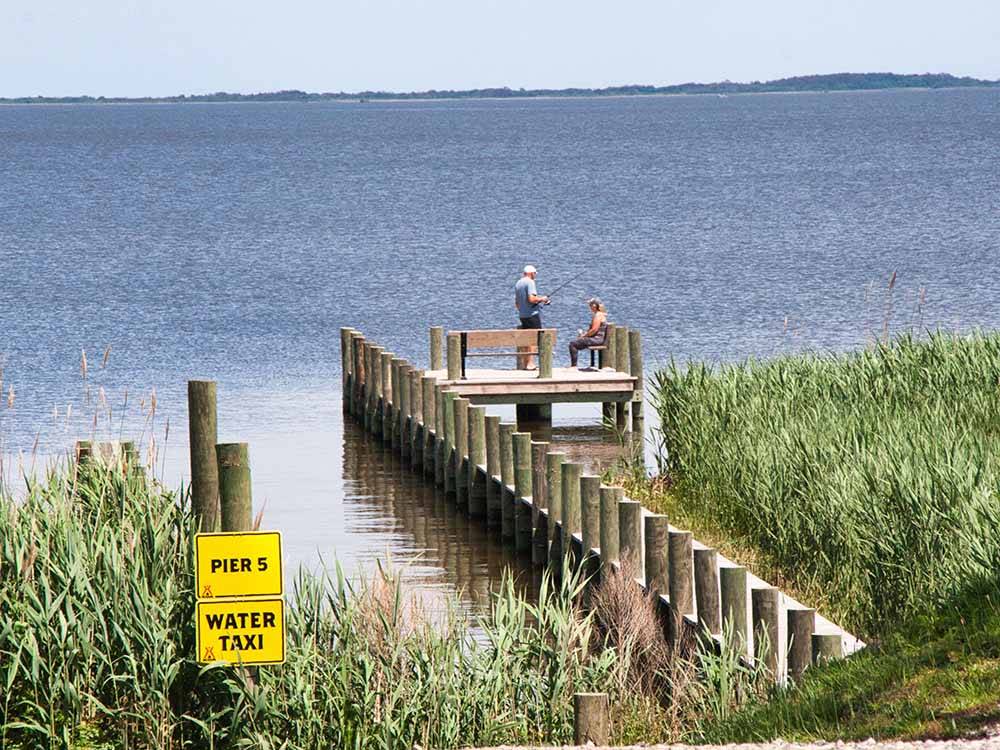 A couple at the end of the pier fishing at OUTER BANKS WEST/CURRITUCK SOUND KOA HOLIDAY