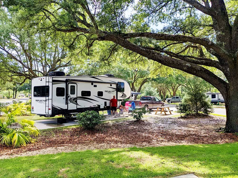 A truck and trailer parked under a tree at SPLASH! RV RESORT & WATERPARK