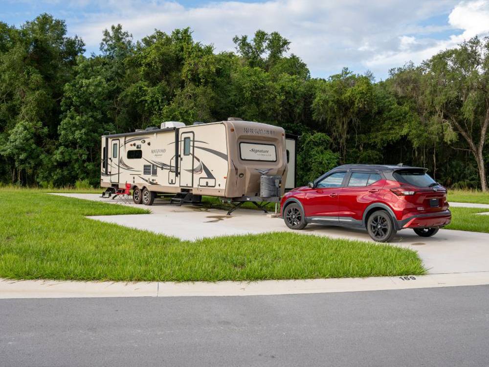 A travel trailler and small SUV parked at a site