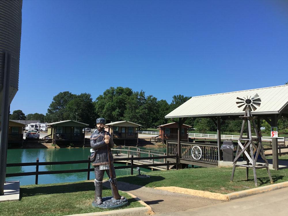 Statue of a pioneer man and a windmill at TEXARKANA RV PARK