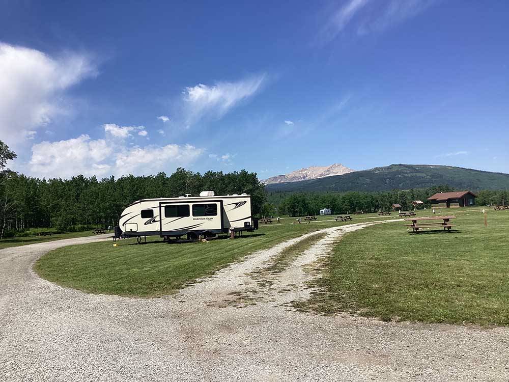 Travel trailer camped in roomy site with mountains in background at CHEWING BLACK BONES CAMPGROUND