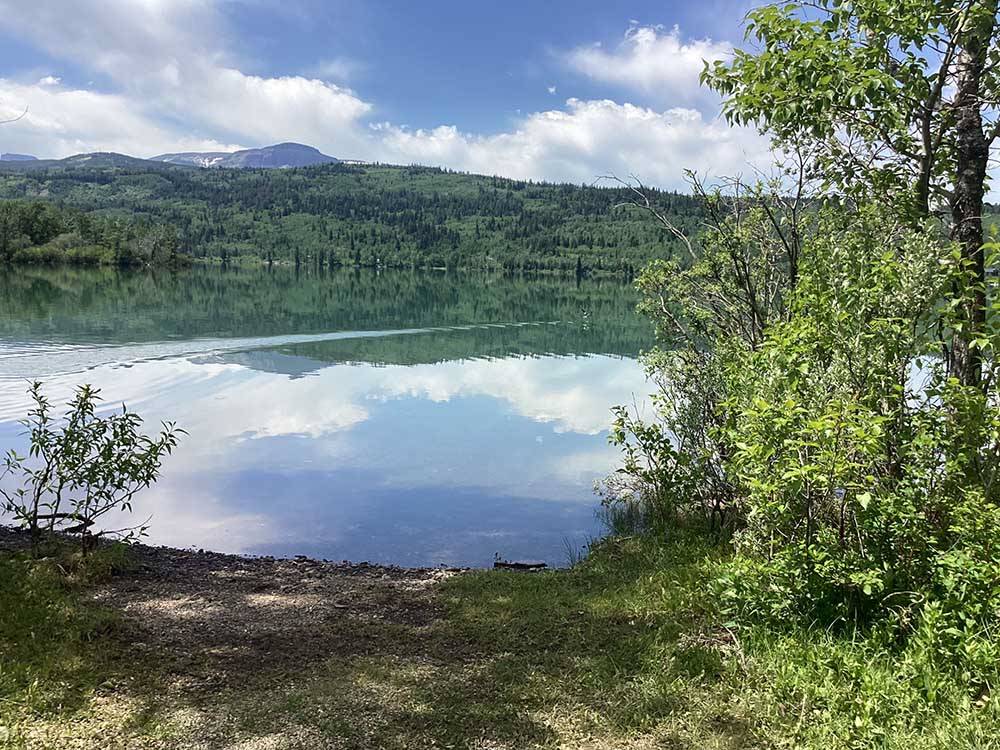 Placid lake reflects surrounding hills and forest at CHEWING BLACK BONES CAMPGROUND