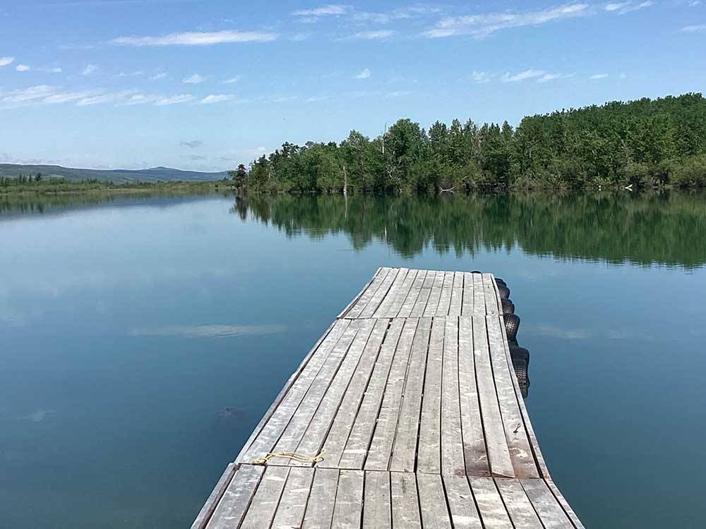 A wooden dock extends into a placid lake at CHEWING BLACK BONES CAMPGROUND
