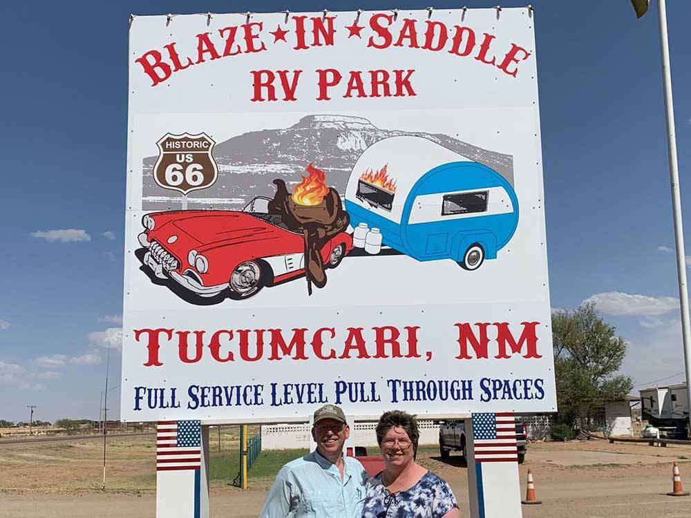 Couple standing in front of sign announcing Blaze-In-Saddle RV Park at BLAZE-IN-SADDLE RV PARK