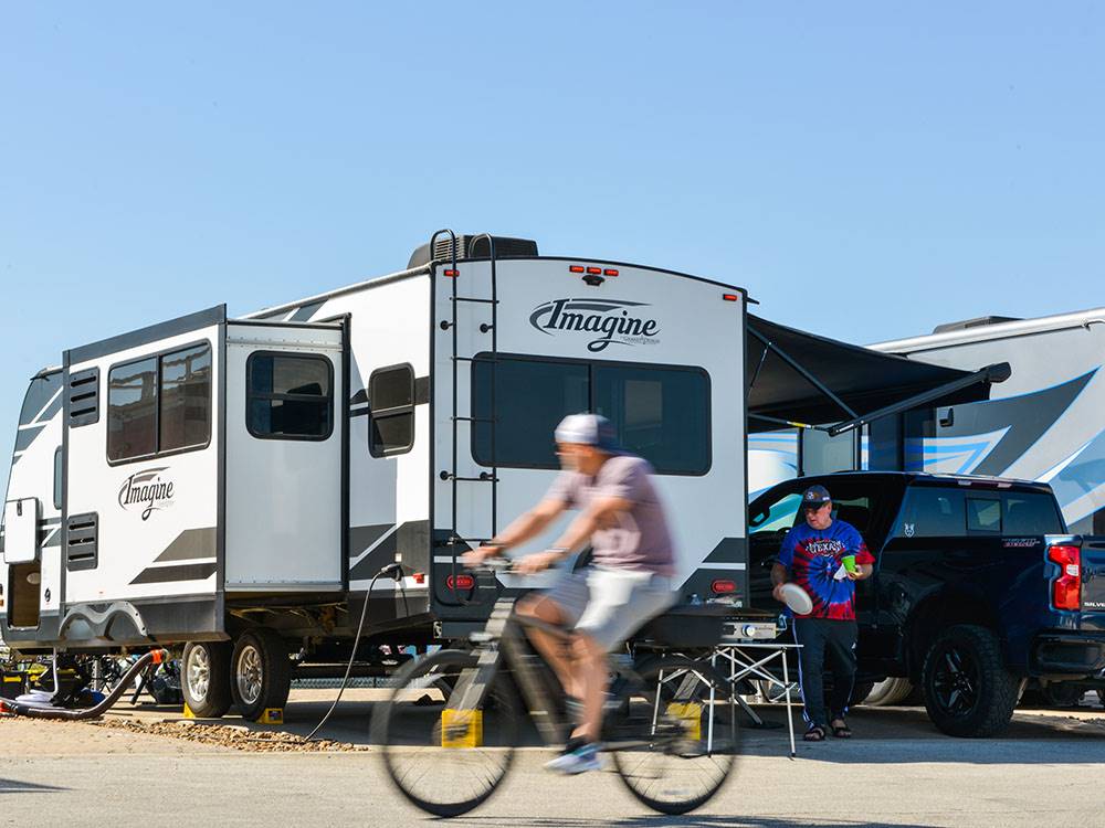 A guy on a bike passing by a parked trailer at COTA CAMPING-PREMIUM RV PARK