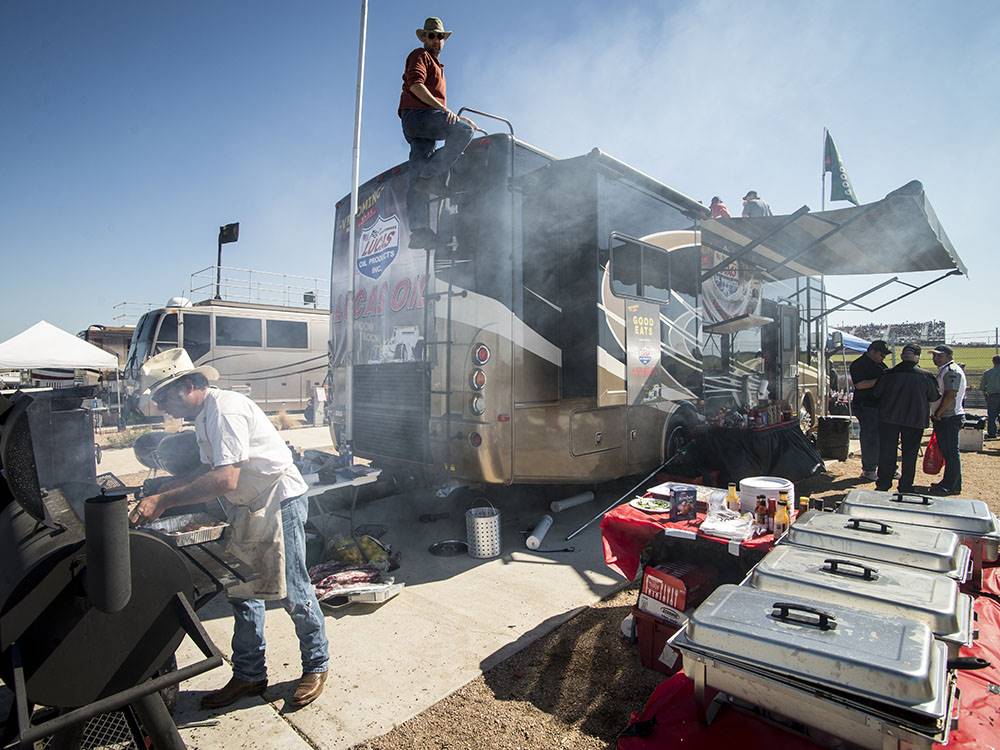 A man barbecuing by a motorhome at COTA CAMPING-PREMIUM RV PARK