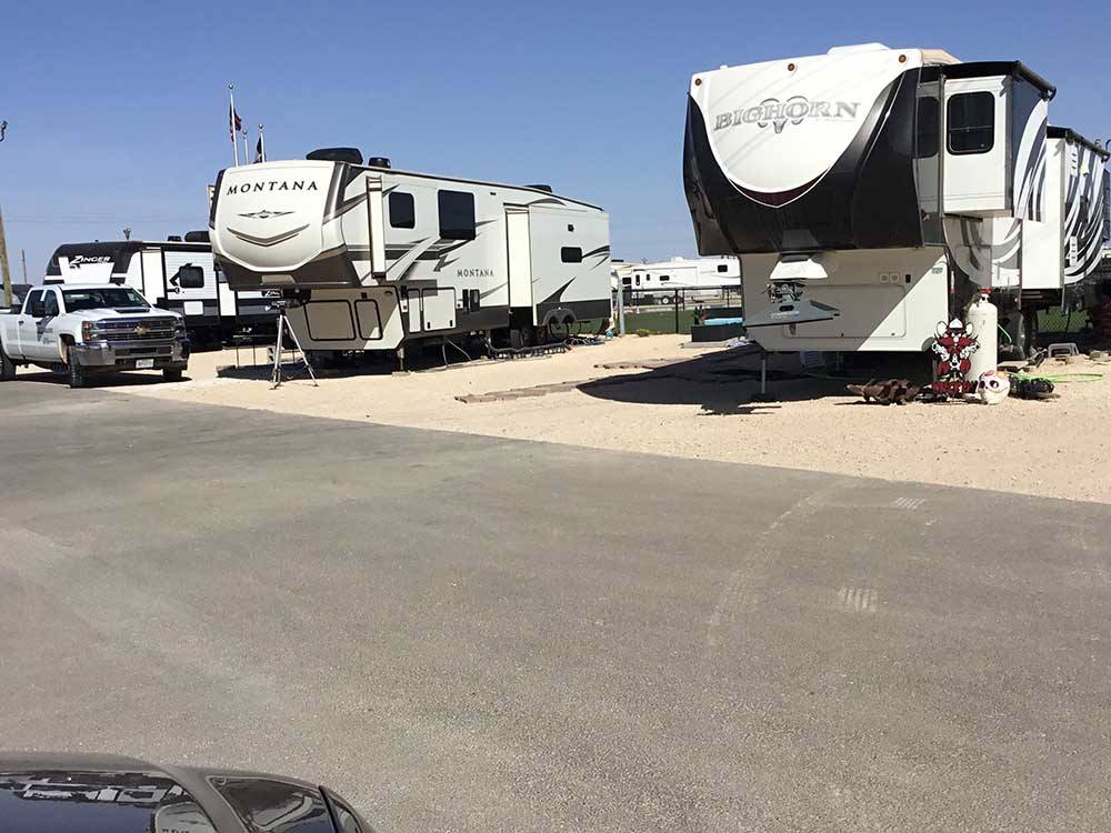 Two 5th wheels on dirt sites along paved road at PARK PLACE RV RESORT