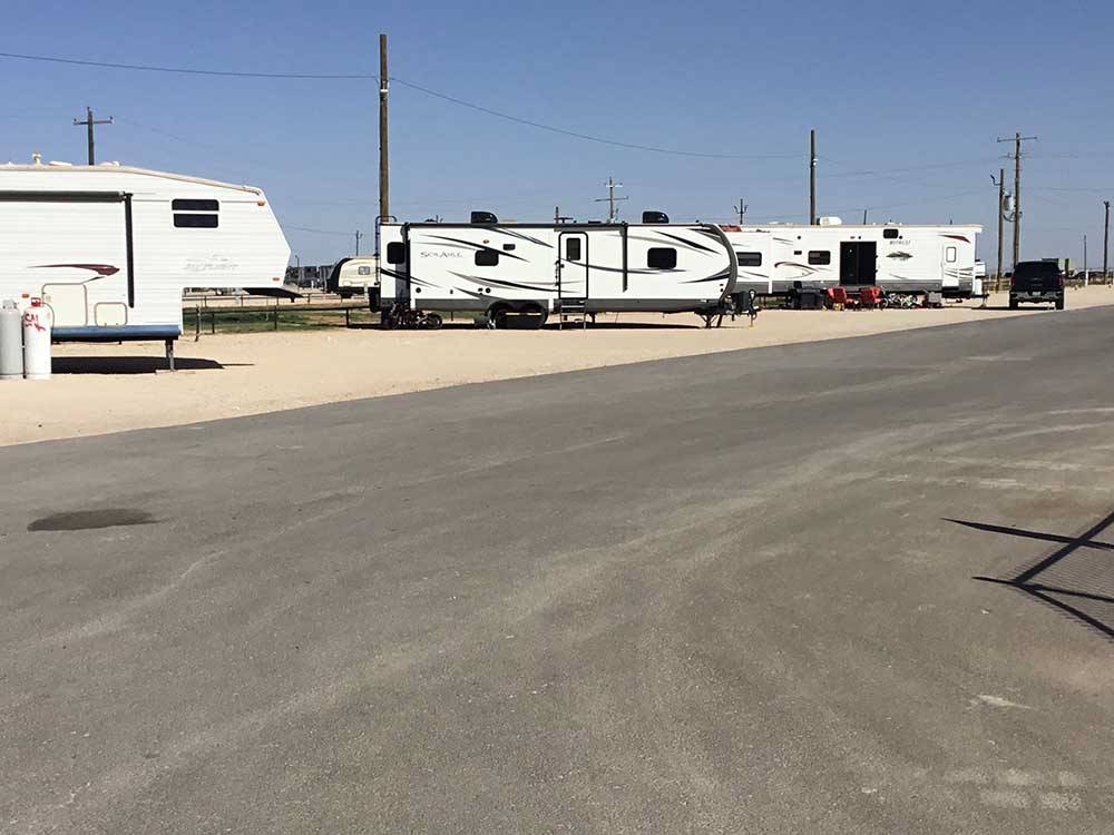 Two travel trailers on dirt sites along paved road at PARK PLACE RV RESORT