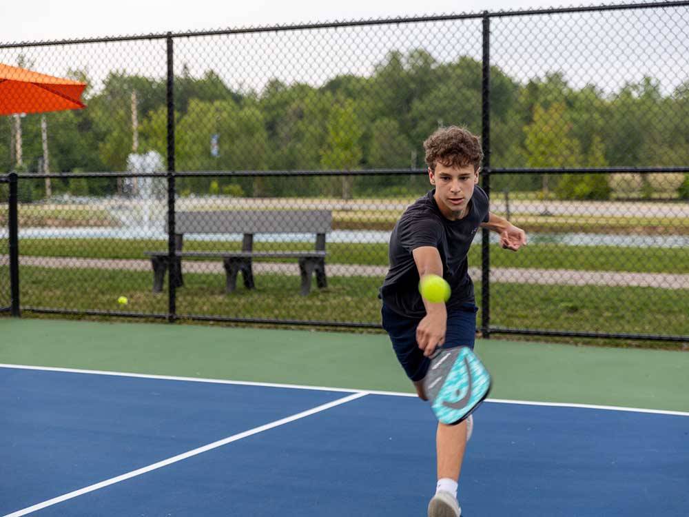 A young man playing tennis at MOTORCOACH RESORT LAKE ERIE SHORES
