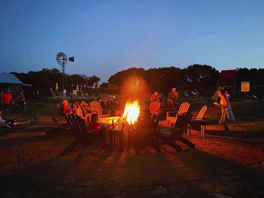 People sitting around a fire pit at dusk at DINOSAUR VALLEY RV PARK
