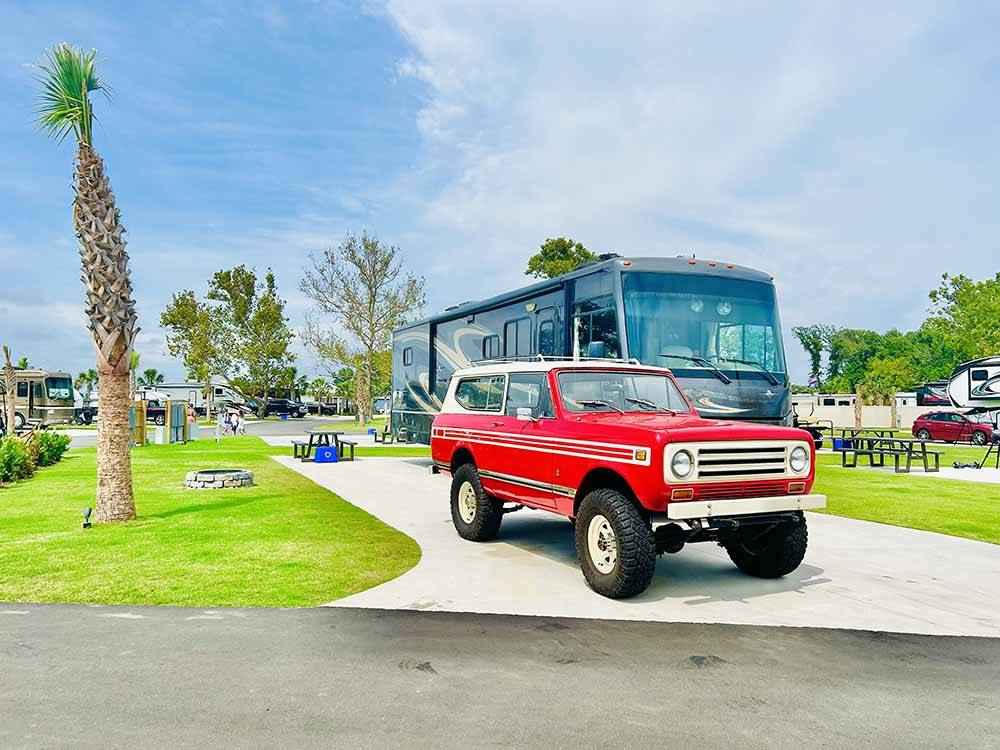 A red truck and motorhome in a cement site at BAREFOOT RV RESORT