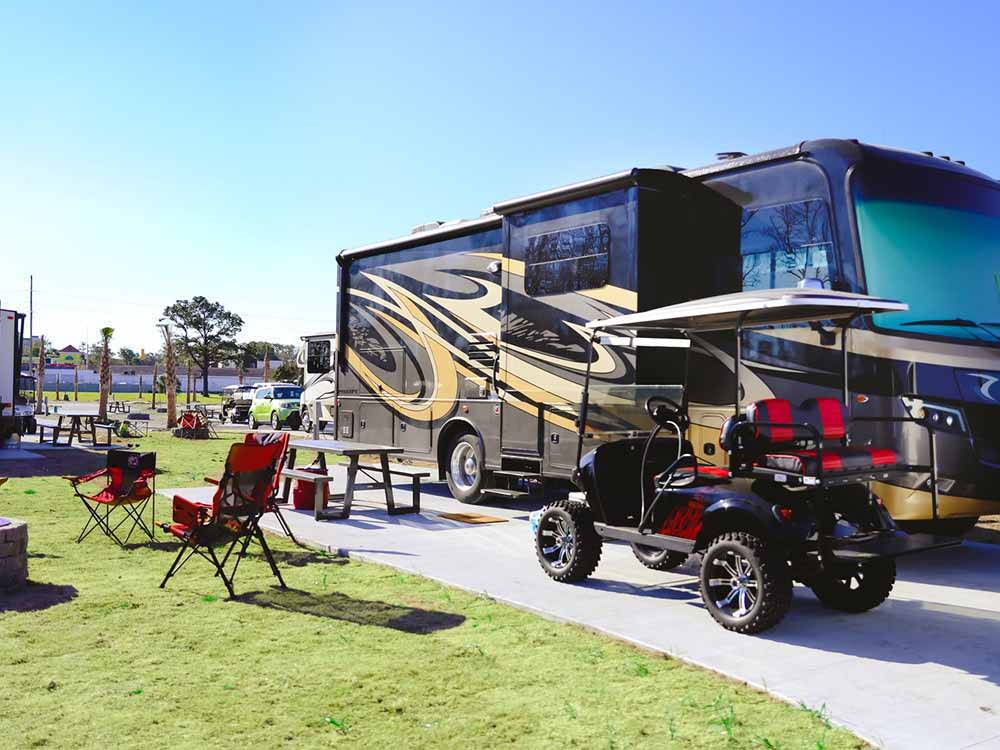 A golf cart and motorhome parked in a site at BAREFOOT RV RESORT