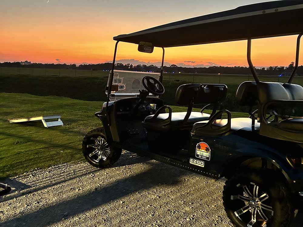 A golf cart parked next to the corn hole game at night at BAREFOOT RV RESORT