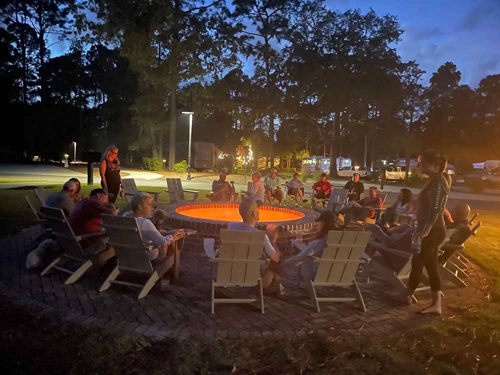 A group of campers sitting around a lit up fire pit at HILTON HEAD NATIONAL RV RESORT