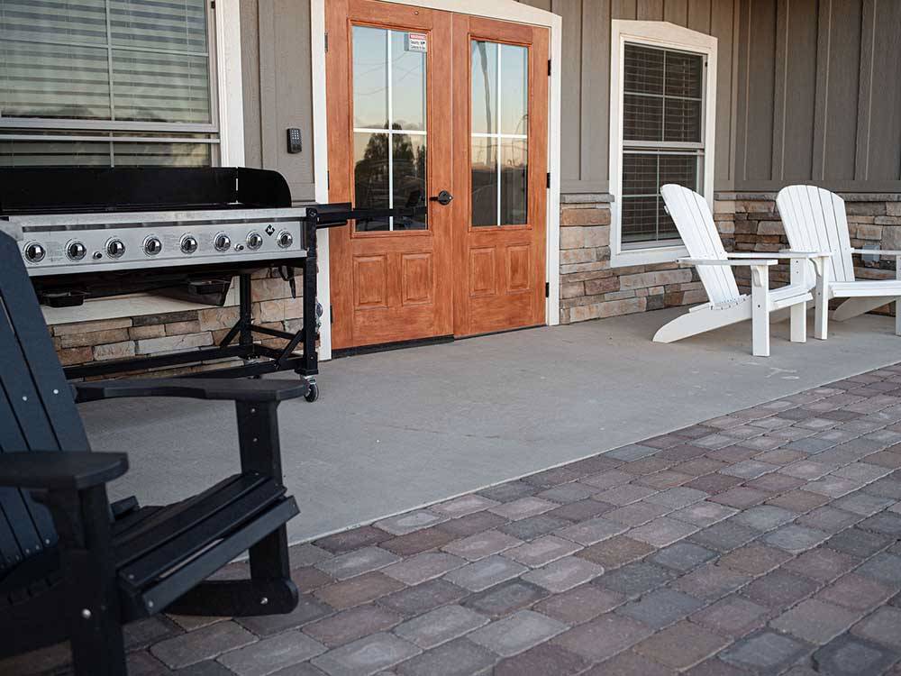 Gas grill and lounge chairs set up outside of main building at COOL SUNSHINE RV PARK