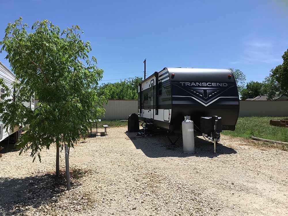 A black travel trailer backed in a site at SUNDANCE RV PARK