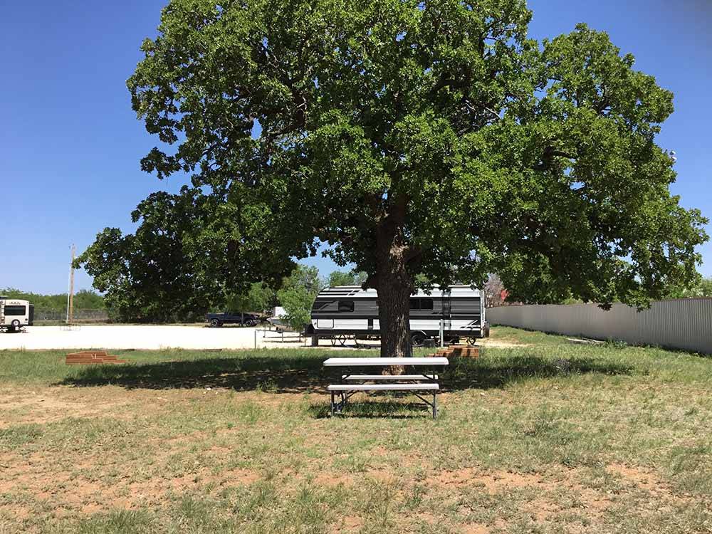 A bench and horseshoe pit under a tree at SUNDANCE RV PARK