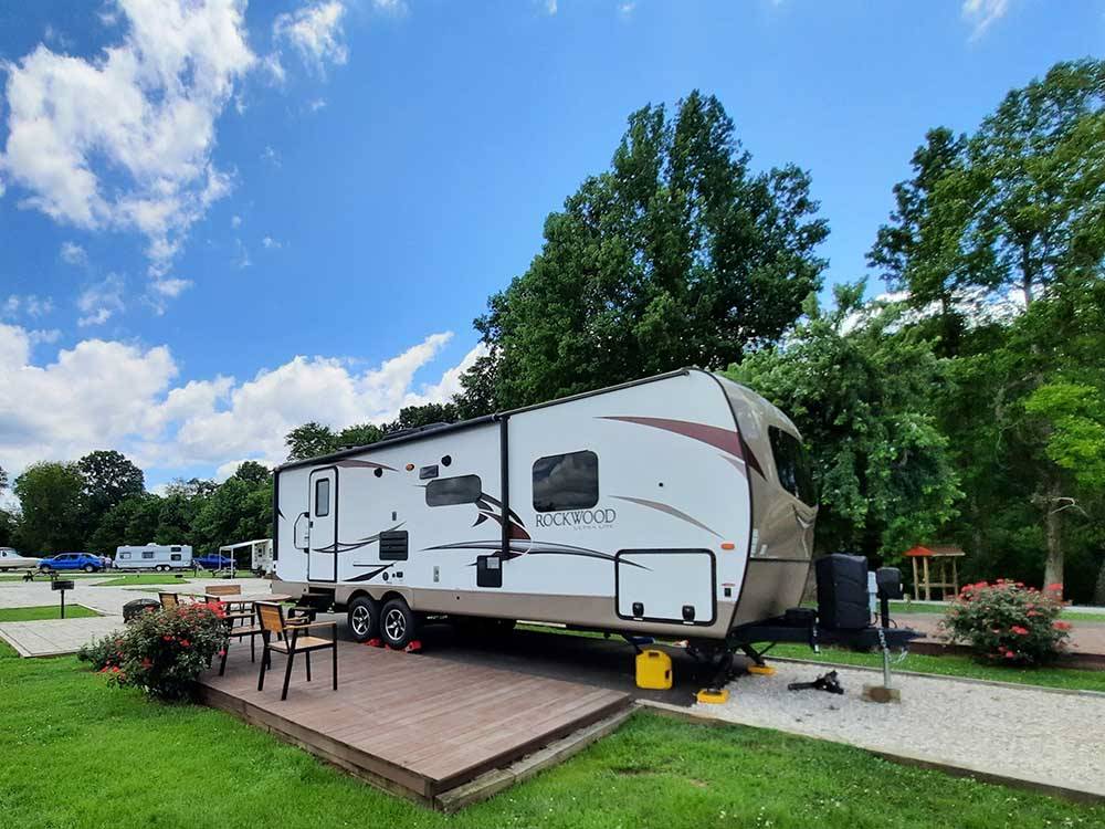 Motorhome in campsite with deck at OUTPOST RV PARK & CAMPGROUND