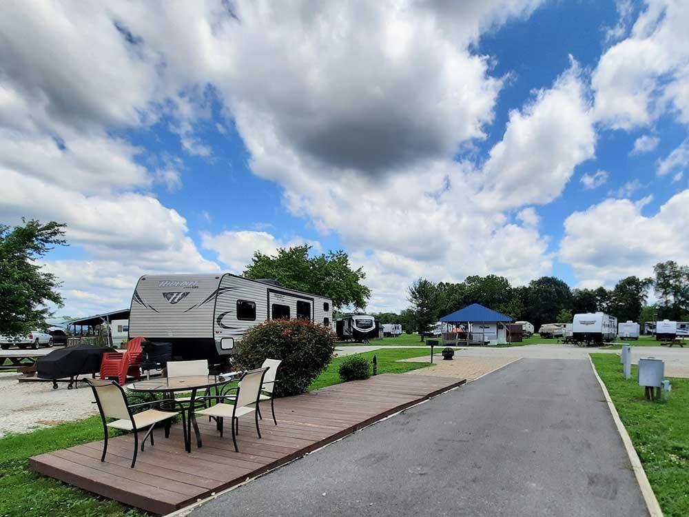 Deck with table and chairs and campers in campsites at OUTPOST RV PARK & CAMPGROUND