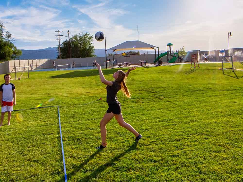 Girl and boy play soccer on grass field at CANYON VIEW RV RESORT