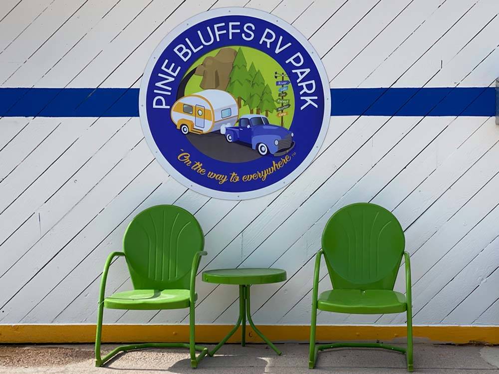 A couple of green chairs in front of a sign at PINE BLUFFS RV RESORT BY RJOURNEY