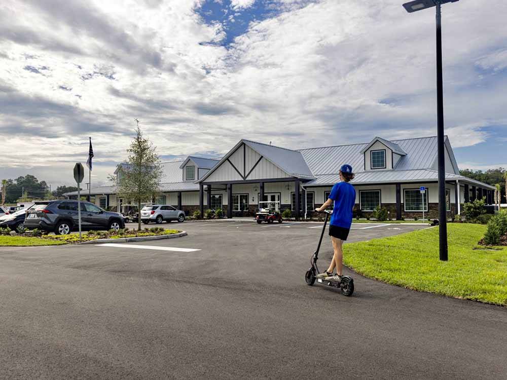 Teen on a scooter riding in front of the office at CHAMPIONS RUN LUXURY RV RESORT